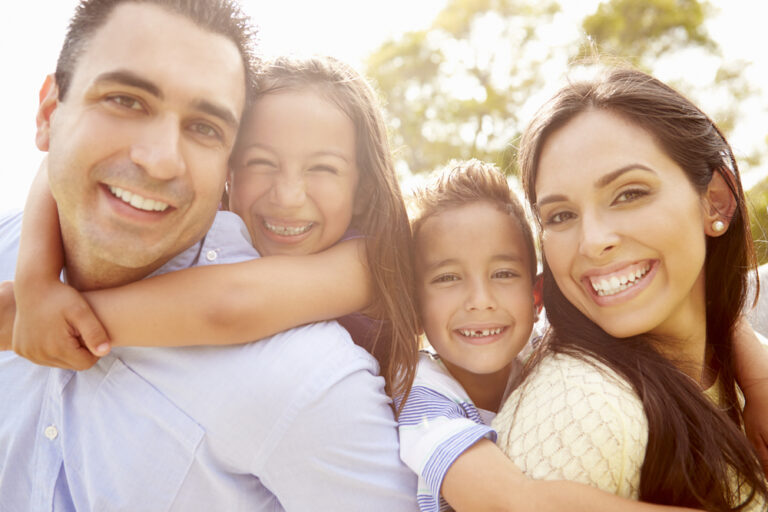 Parents,Giving,Children,Piggyback,Ride,In,Garden